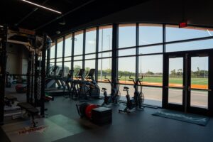 Inside the UT Rio Grande Valley weight room looking out a window that views the football field.