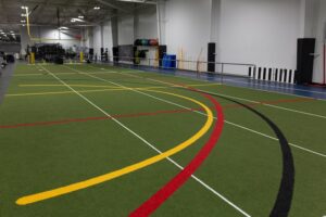 image shows the inside of an athletic training facility featuring a turf field