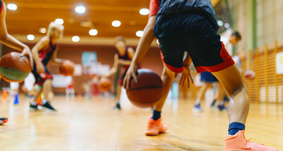 image shows a basketball player dribbling toward defenders