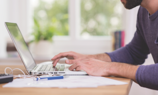 image shows someone typing on a laptop
