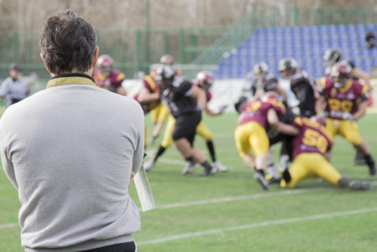 A football coach watches players in action