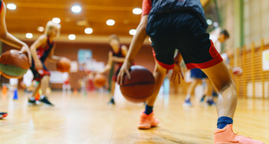 image shows a basketball player dribbling toward defenders