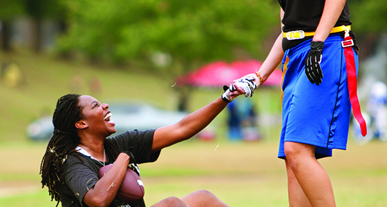image shows a girls flag football player being helped up on the field