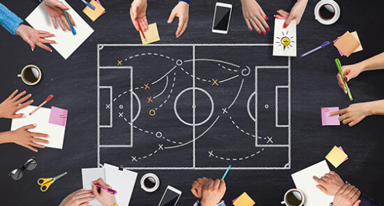 image shows a soccer field graphic with hands and writing utensils around it